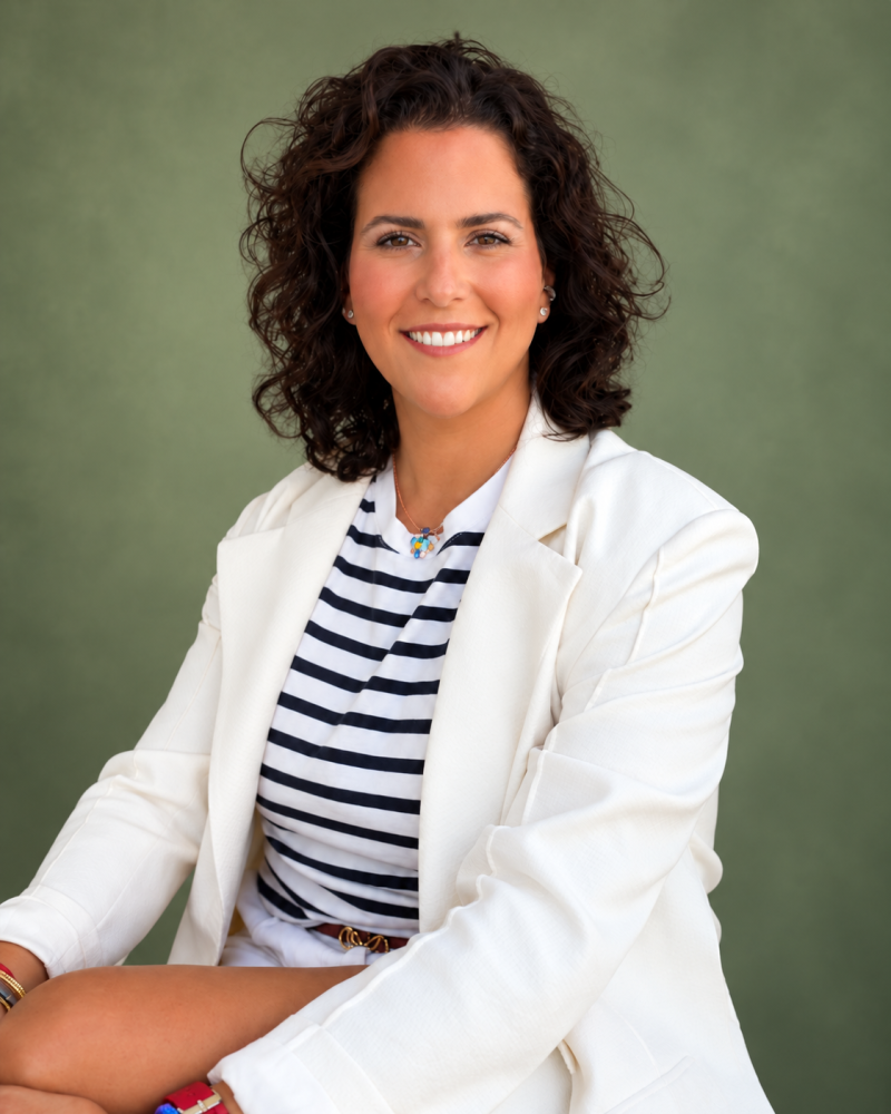Retrato profesional de Alicia, interiorista de Martinas Interiorismo, con blazer blanco y camiseta de rayas.
